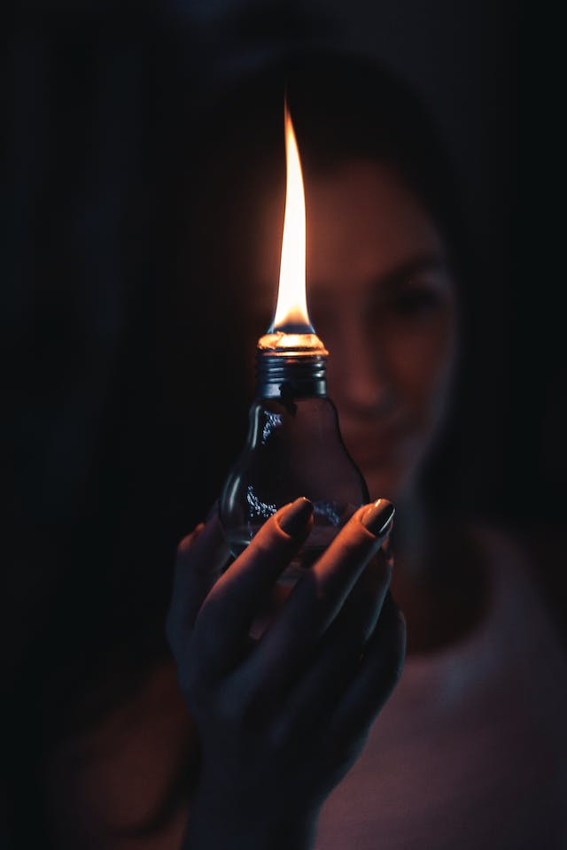 Foto van een vrouw die een olielamp in de vorm van een gloeilamp met een e27 fitting voor zich houdt.